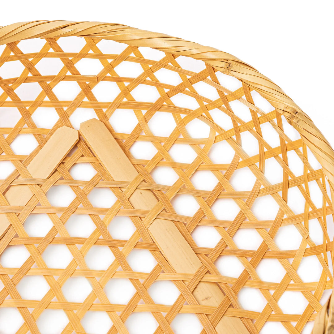 A medium round handwoven bamboo serving basket with a hexagonal mesh pattern lid resting on the woven border