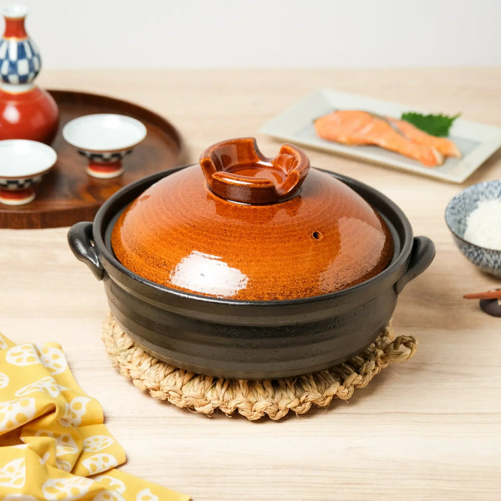 Traditional Japanese clay donabe pot with brown lid and black base, ideal for cooking rice, hotpot, and stews.