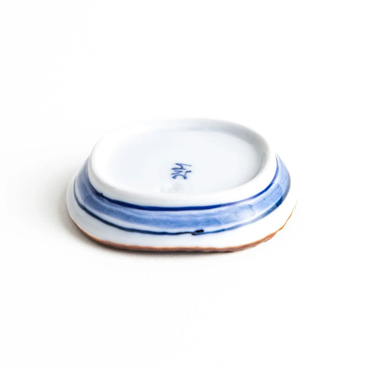 A round plate featuring a large, bold blue flower with a textured brown rim.