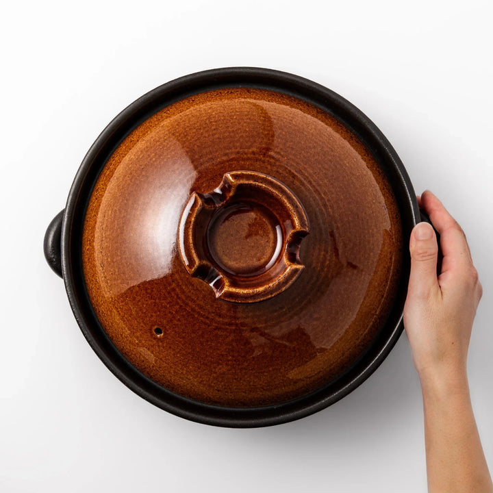 Japanese donabe clay pot with brown glazed lid and black base induction compatible for family hot pot.