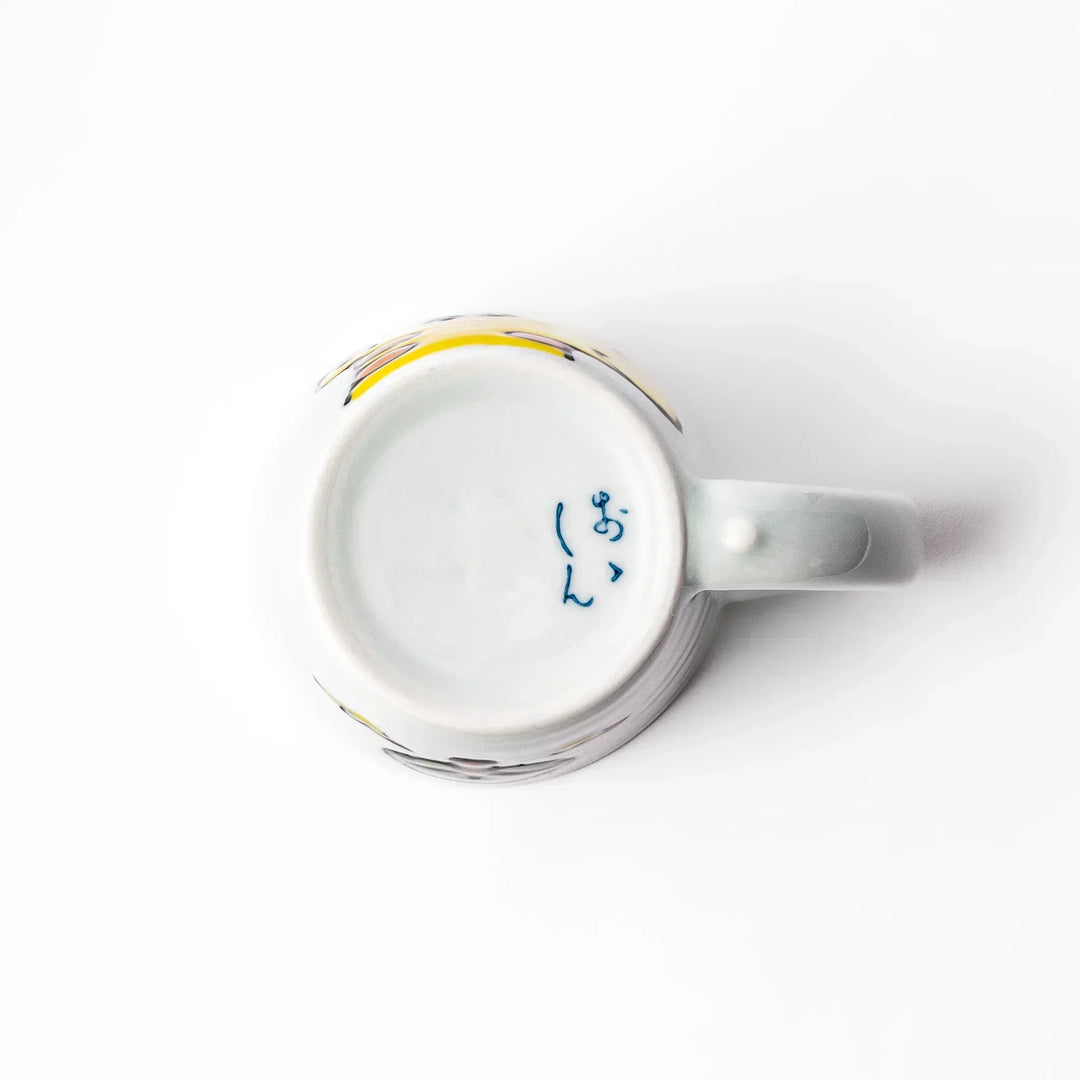 White ceramic kids’ mug with yellow giraffe and green ossicones, featuring a round handle and yellow interior.