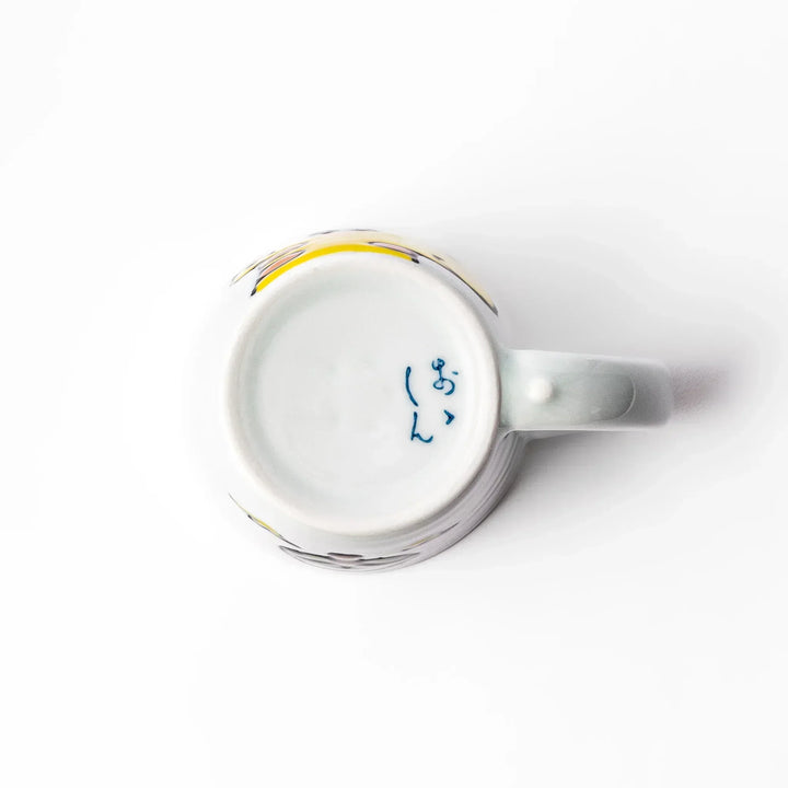 White ceramic kids’ mug with yellow giraffe and green ossicones, featuring a round handle and yellow interior.
