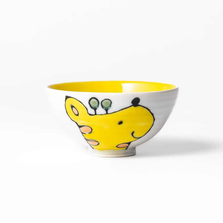 White ceramic kids rice bowl with smiling yellow giraffe illustration, vibrant yellow interior, round footed base