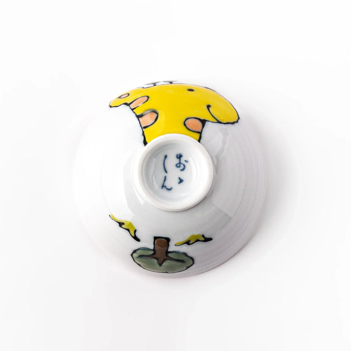 White ceramic kids rice bowl with smiling yellow giraffe illustration, vibrant yellow interior, round footed base
