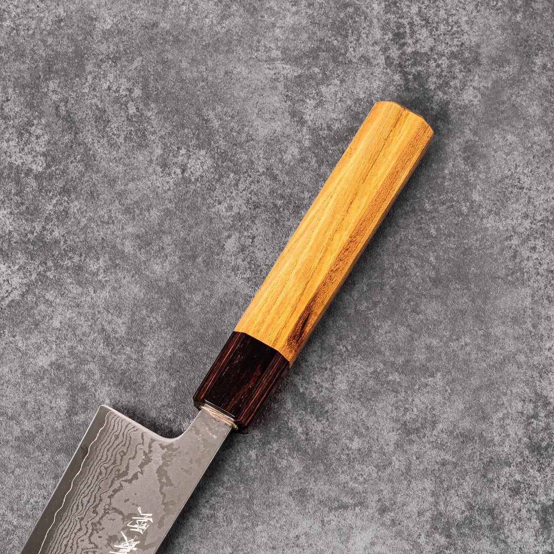 Japanese Damascus gyuto knife featuring a layered steel blade and natural wood handle displayed on gray stone background.