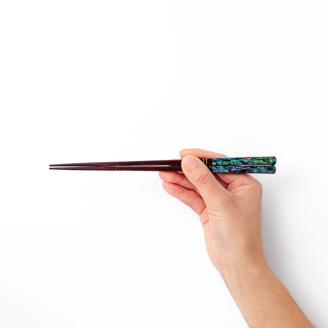 Japanese lacquer chopsticks with shimmering abalone shell inlay and deep red finish, handcrafted for elegant dining.