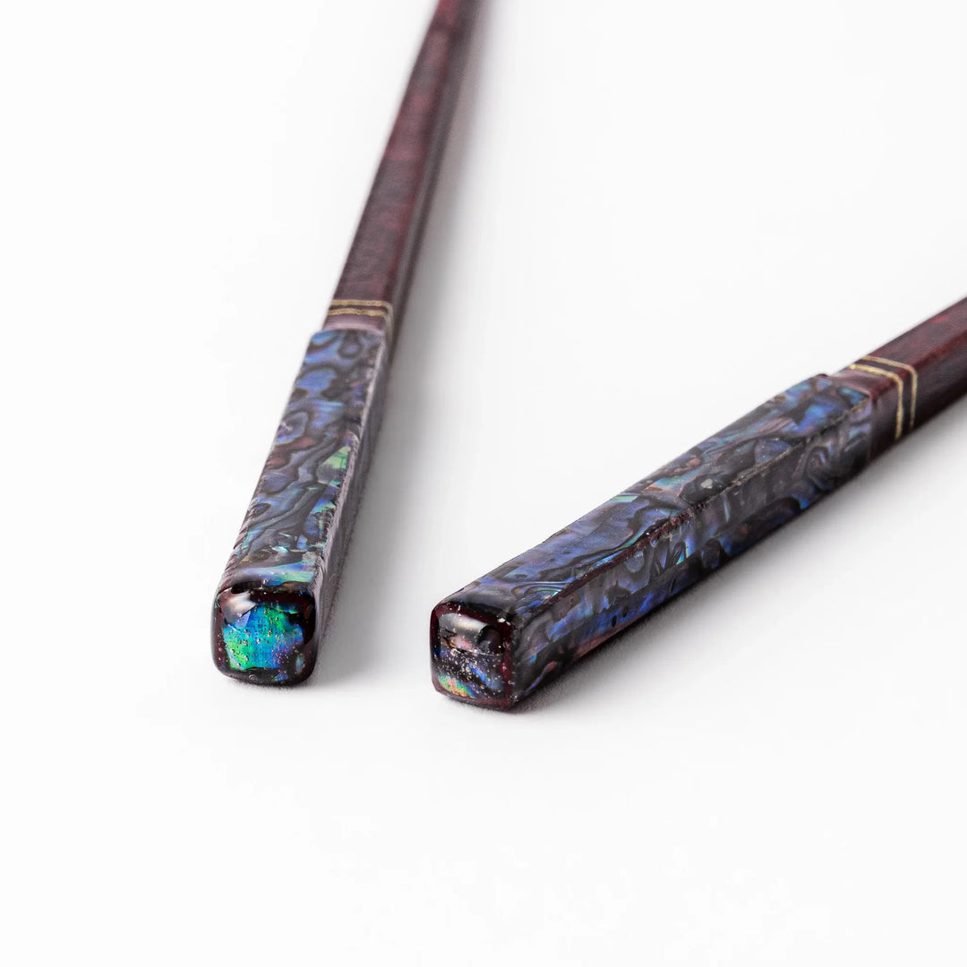 Japanese lacquer chopsticks with shimmering abalone shell inlay and deep red finish, handcrafted for elegant dining.