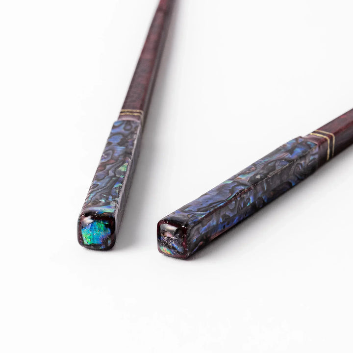 Japanese lacquer chopsticks with shimmering abalone shell inlay and deep red finish, handcrafted for elegant dining.