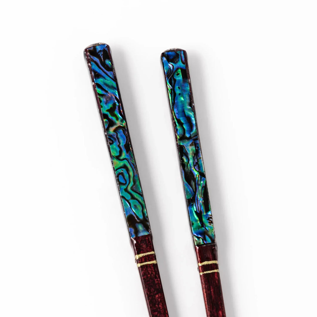 Japanese lacquer chopsticks with shimmering abalone shell inlay and deep red finish, handcrafted for elegant dining.