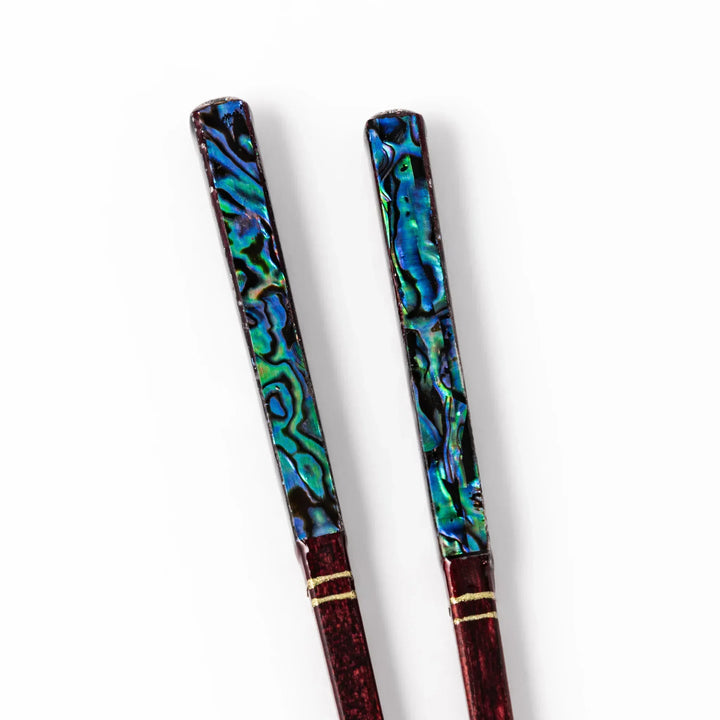 Japanese lacquer chopsticks with shimmering abalone shell inlay and deep red finish, handcrafted for elegant dining.