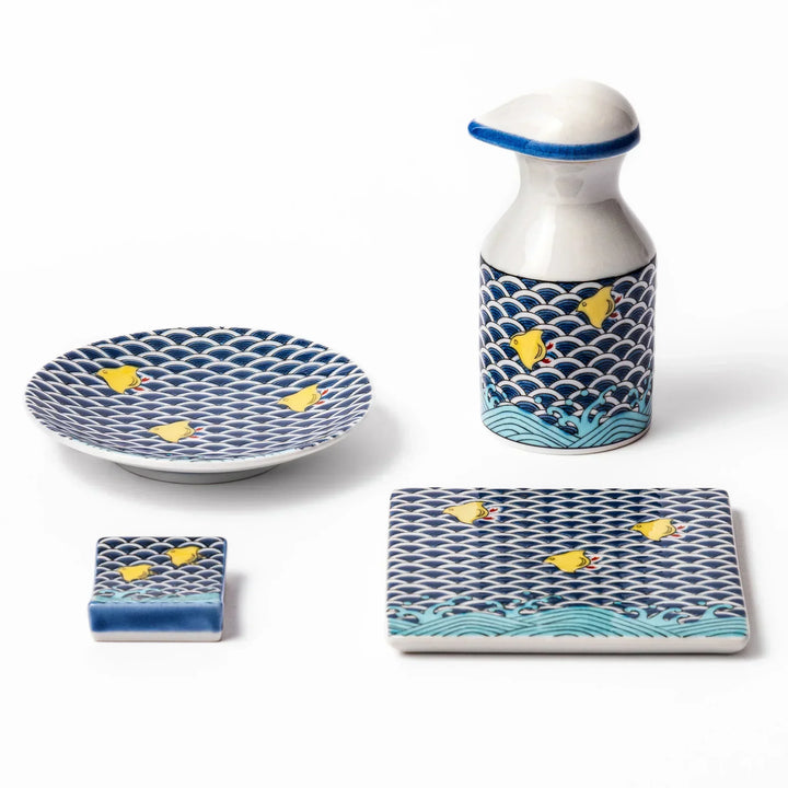 Japanese ceramic tableware set with blue wave pattern and yellow shorebirds including dispenser dish and rest.