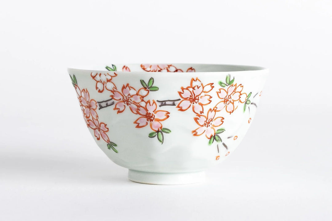 White porcelain bowl with hand-painted pink sakura blossoms and green leaves, showcasing a delicate spring motif.