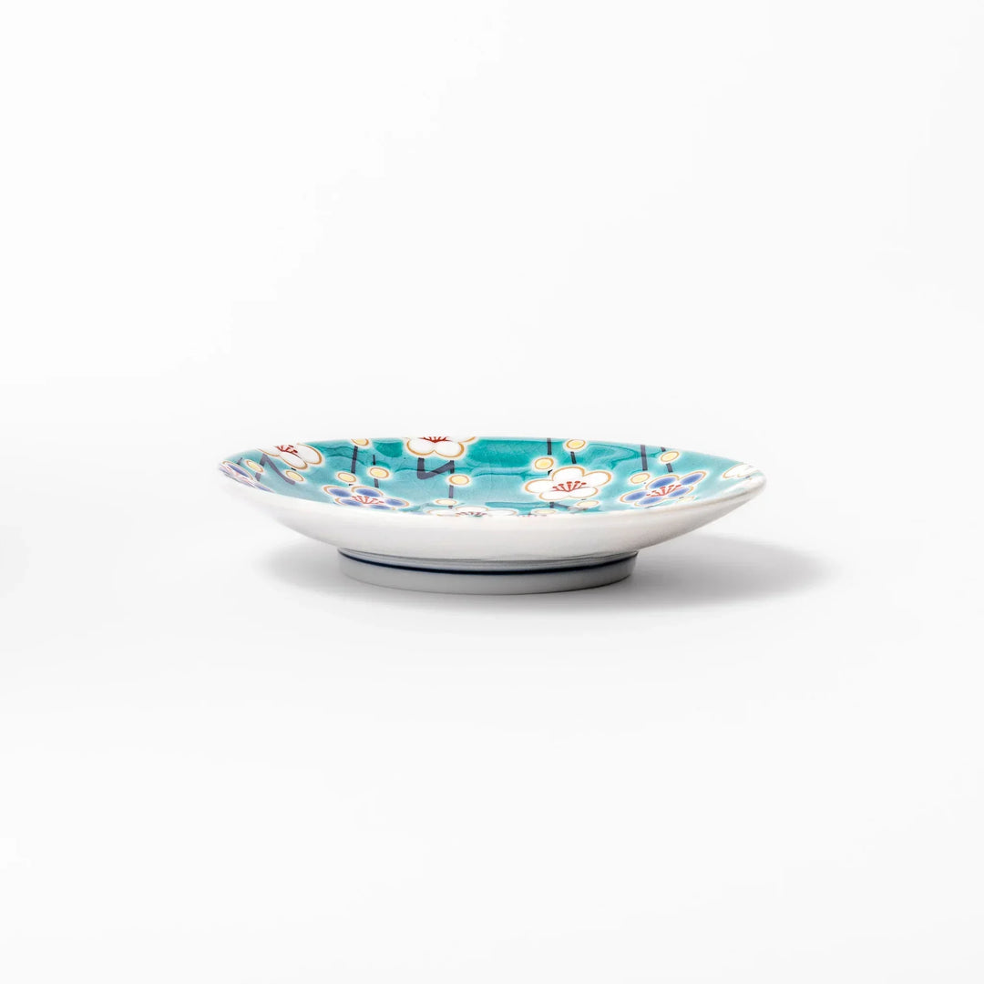 Round Japanese ceramic sauce dish with teal background and white blue plum blossom motifs for condiments.