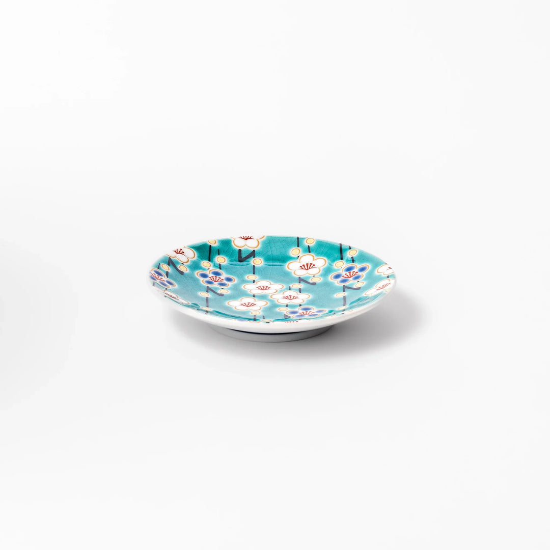 Round Japanese ceramic sauce dish with teal background and white blue plum blossom motifs for condiments.