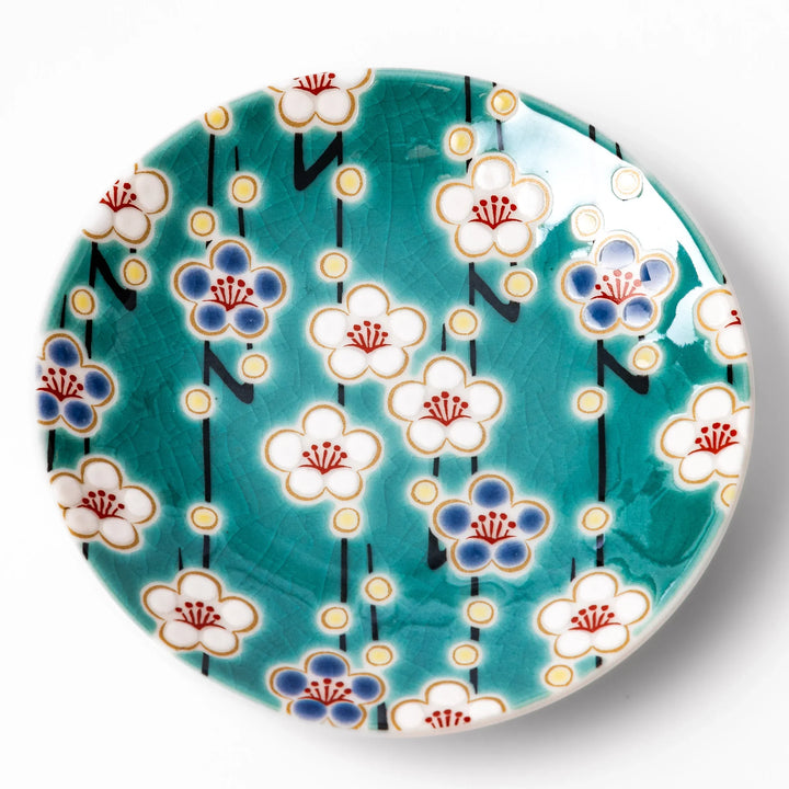 Round Japanese ceramic sauce dish with teal background and white blue plum blossom motifs for condiments.