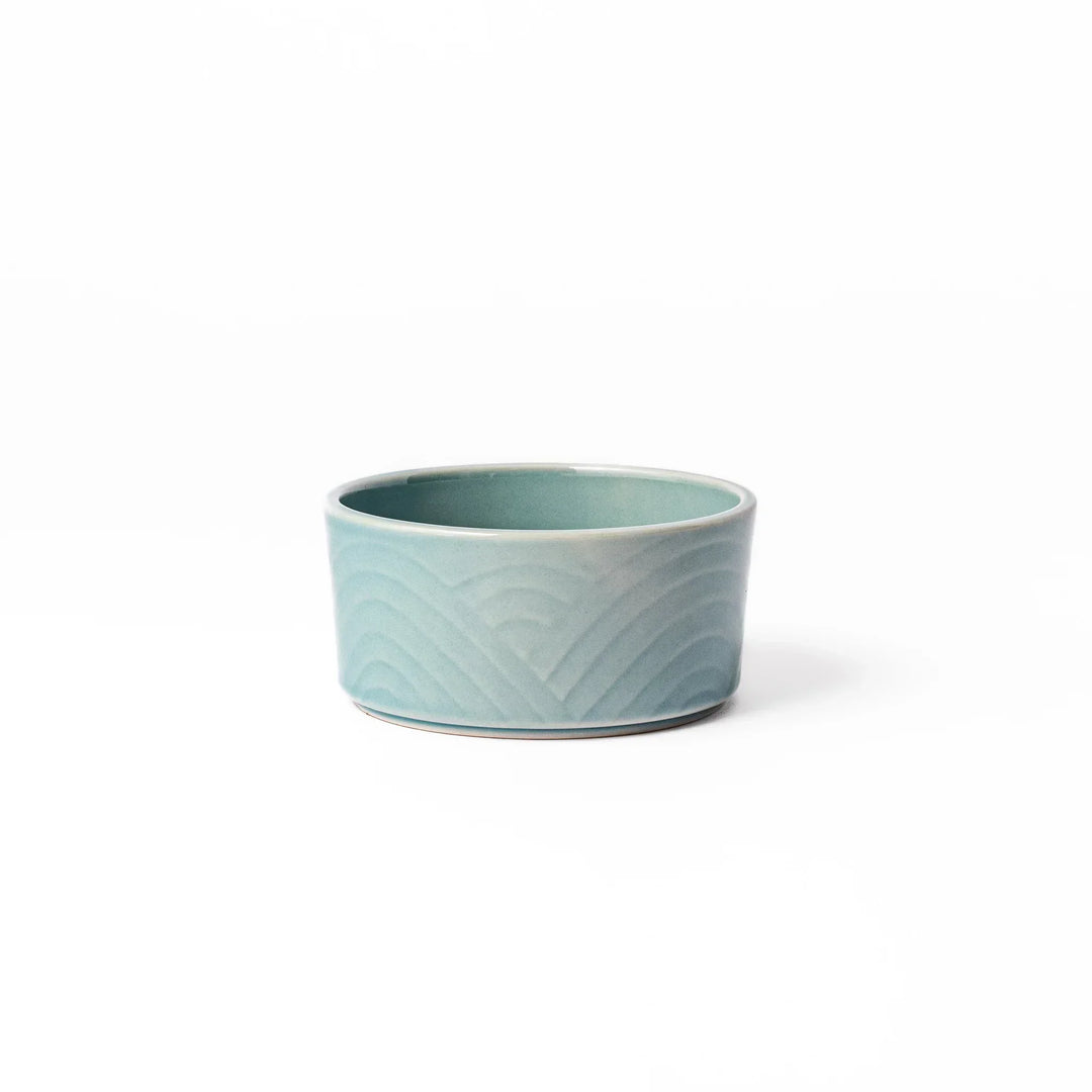Light blue stackable Japanese porcelain bowl with embossed Seigaiha wave pattern and smooth matte texture.