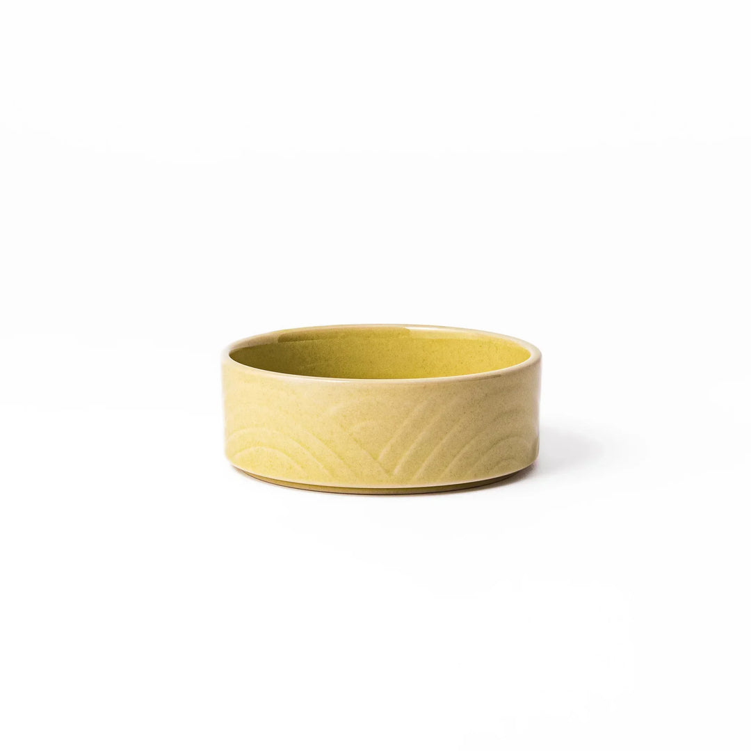 Small yellow Japanese porcelain bowl with embossed Seigaiha wave pattern matte finish and minimalist design.