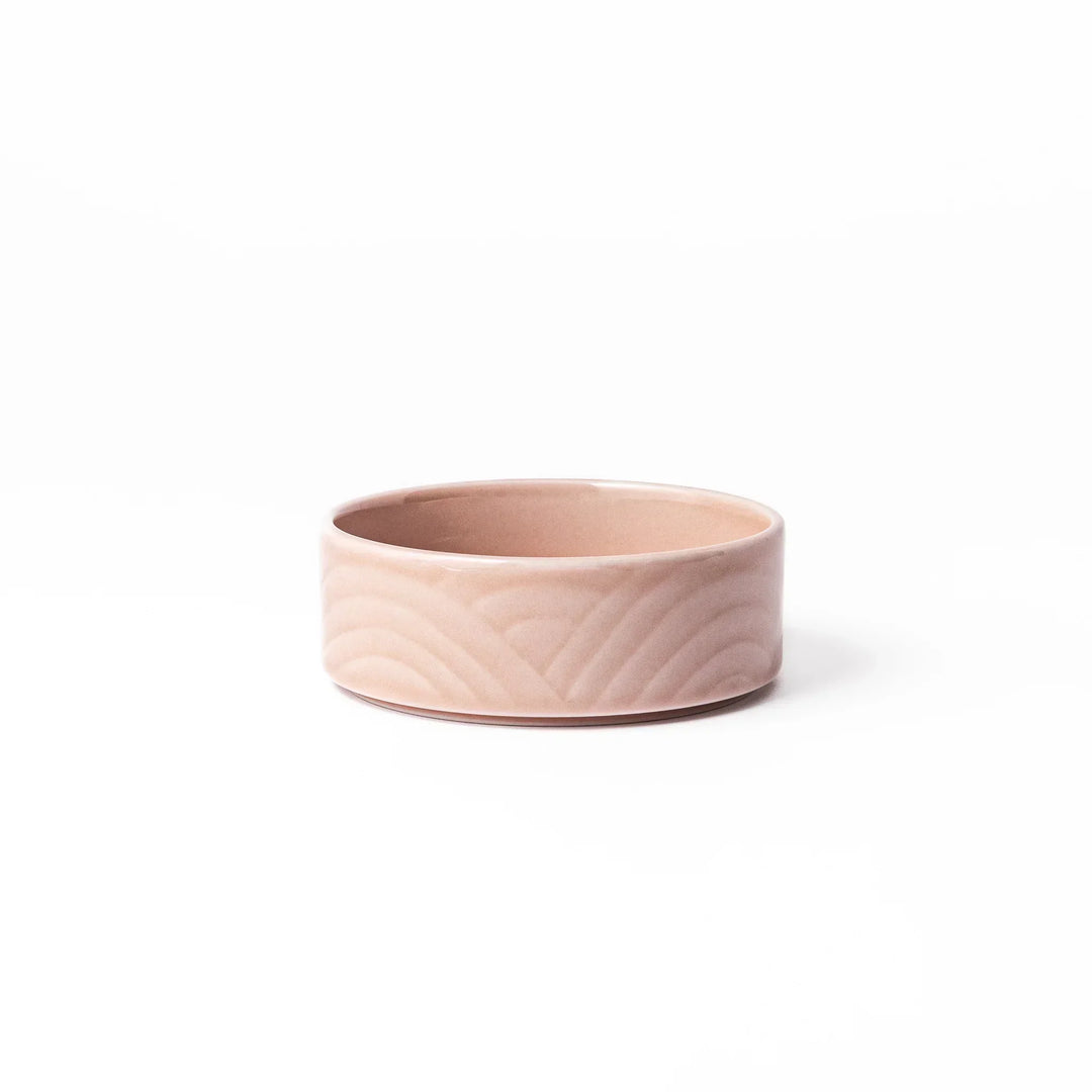 Light pink Japanese porcelain bowl with embossed wave pattern glossy finish and simple cylindrical shape.