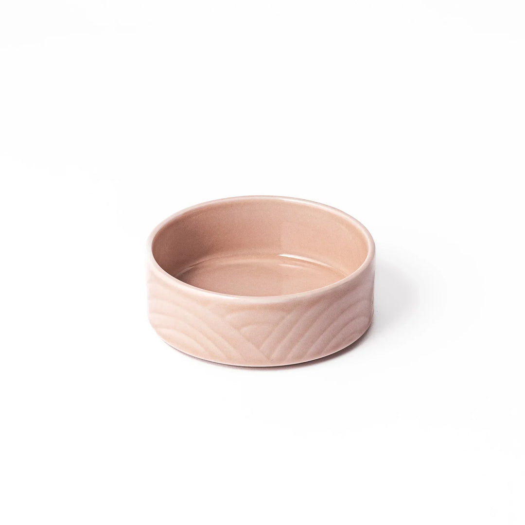 Light pink Japanese porcelain bowl with embossed wave pattern glossy finish and simple cylindrical shape.