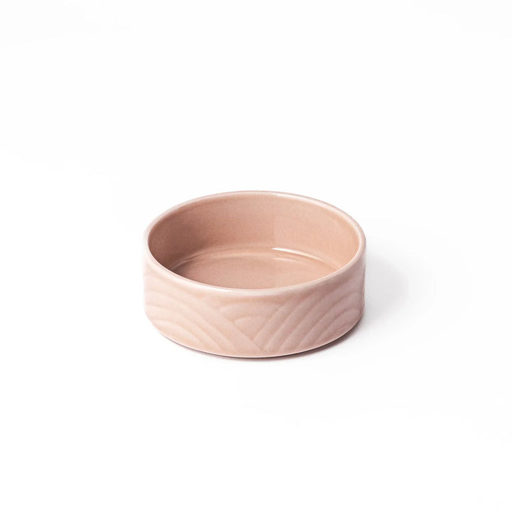 Light pink Japanese porcelain bowl with embossed wave pattern glossy finish and simple cylindrical shape.