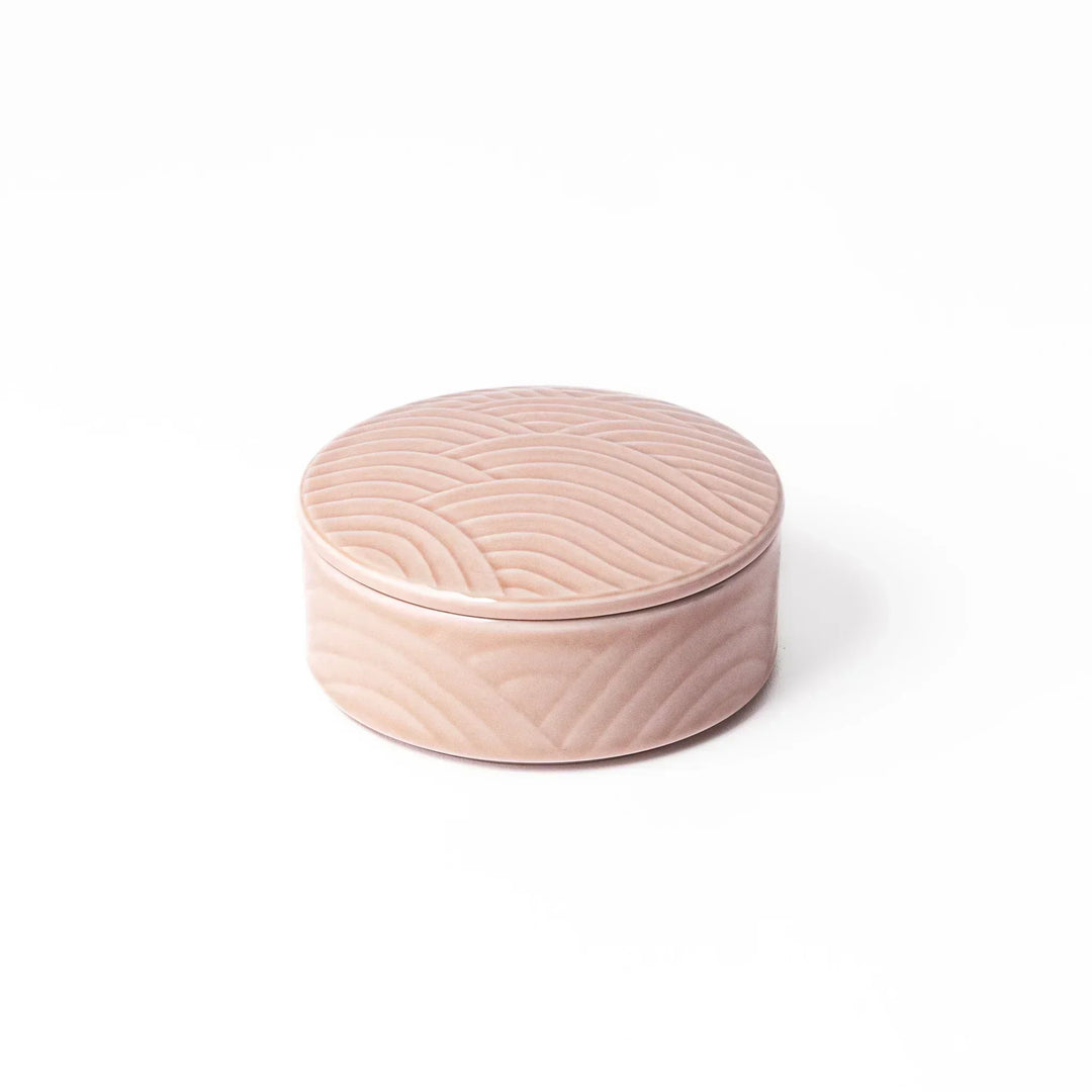 Light pink Japanese porcelain bowl with embossed wave pattern glossy finish and simple cylindrical shape.