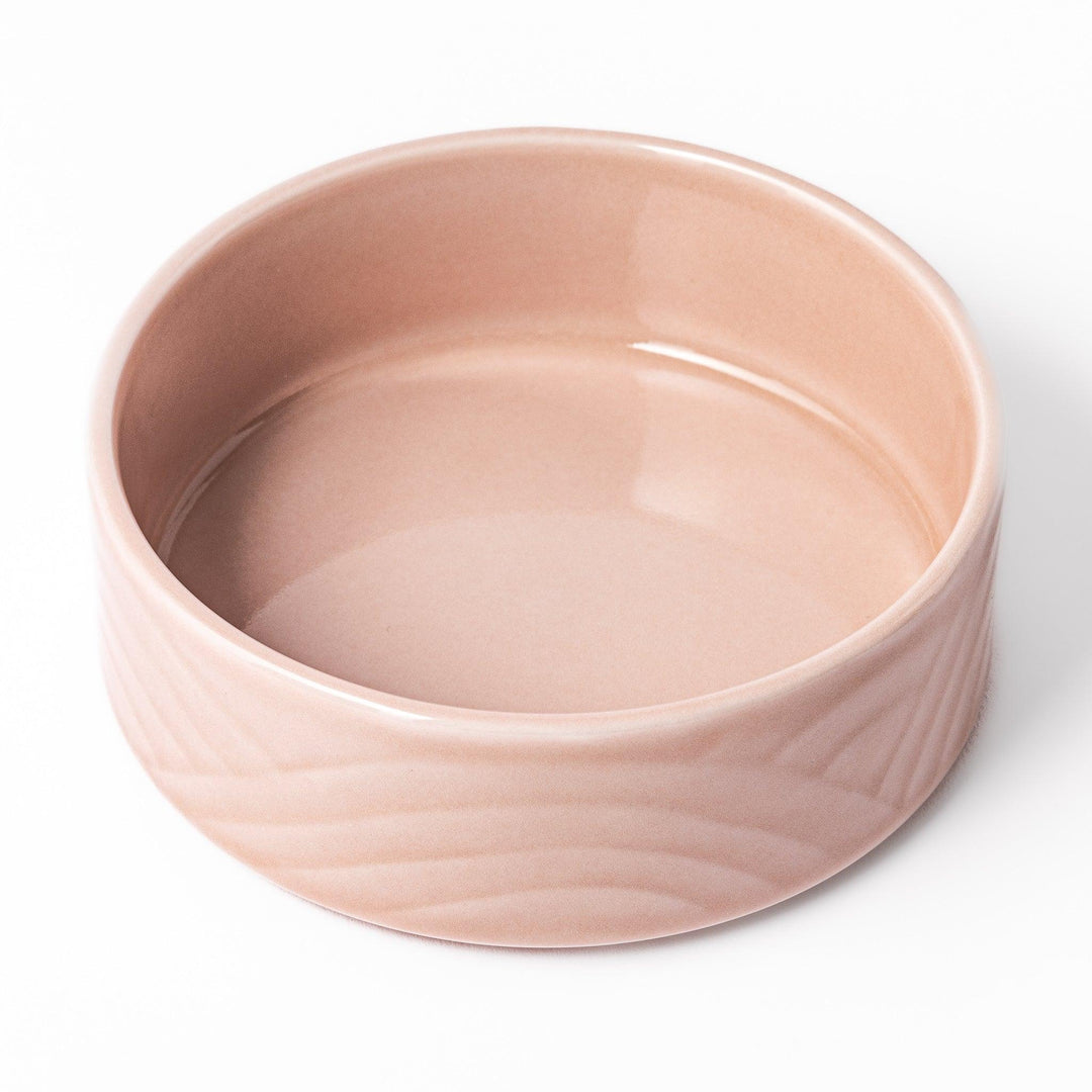 Light pink Japanese porcelain bowl with embossed wave pattern glossy finish and simple cylindrical shape.