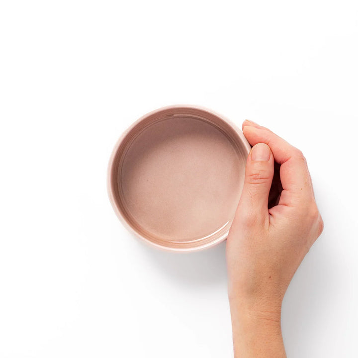 Light pink Japanese porcelain bowl with embossed wave pattern glossy finish and simple cylindrical shape.
