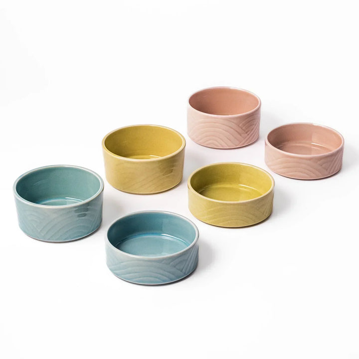 Set of six pastel Japanese porcelain bowls in blue yellow and pink with embossed Seigaiha wave patterns.