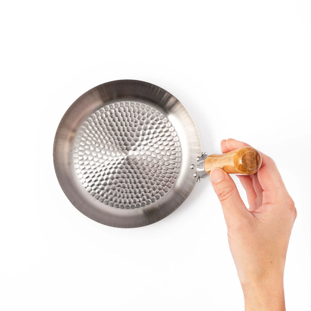 Japanese stainless steel donburi pot with wooden handle and hammered base for heating rice bowls and sauces.