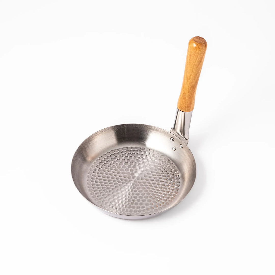 Japanese stainless steel donburi pot with wooden handle and hammered base for heating rice bowls and sauces.