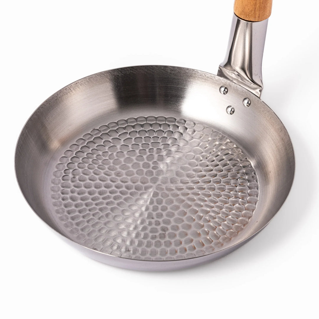 Japanese stainless steel donburi pot with wooden handle and hammered base for heating rice bowls and sauces.