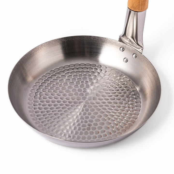 Japanese stainless steel donburi pot with wooden handle and hammered base for heating rice bowls and sauces.