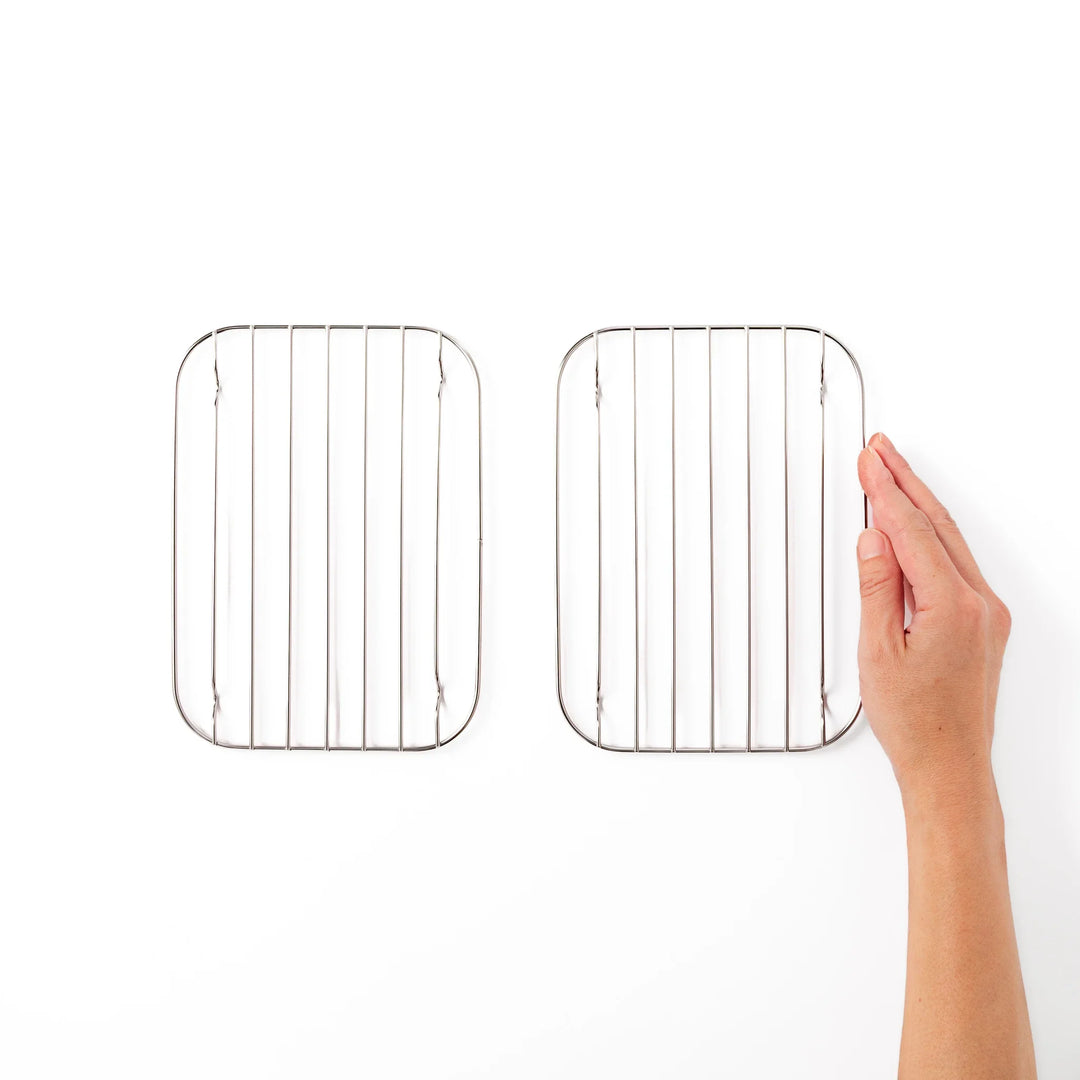 Hand holding one of two small Japanese stainless steel prep tray wire racks for size comparison