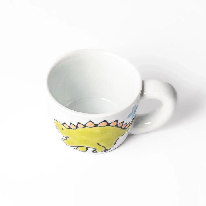 White ceramic kids mug featuring green stegosaurus dinosaur with round handle, shown on white background