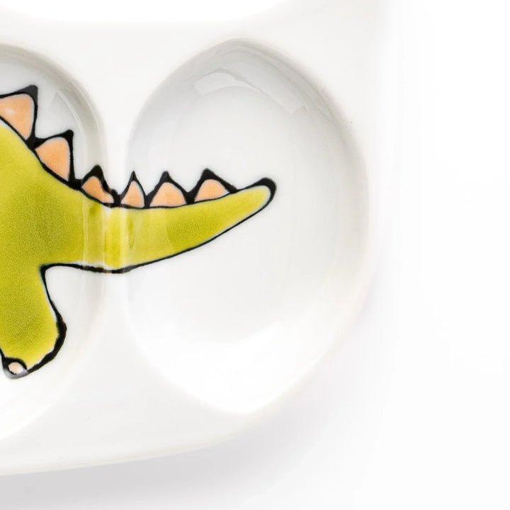 White ceramic kids divided plate with green stegosaurus, red erupting volcano, pink pterodactyl and blue cloud motifs