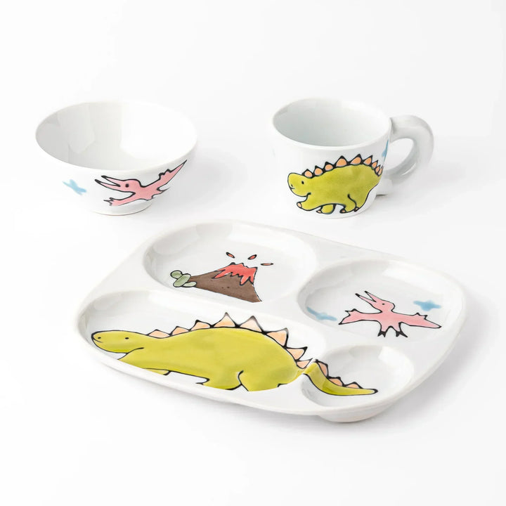 White ceramic kids mug, rice bowl and divided plate set with green stegosaurus, pink pterodactyl and volcano motifs