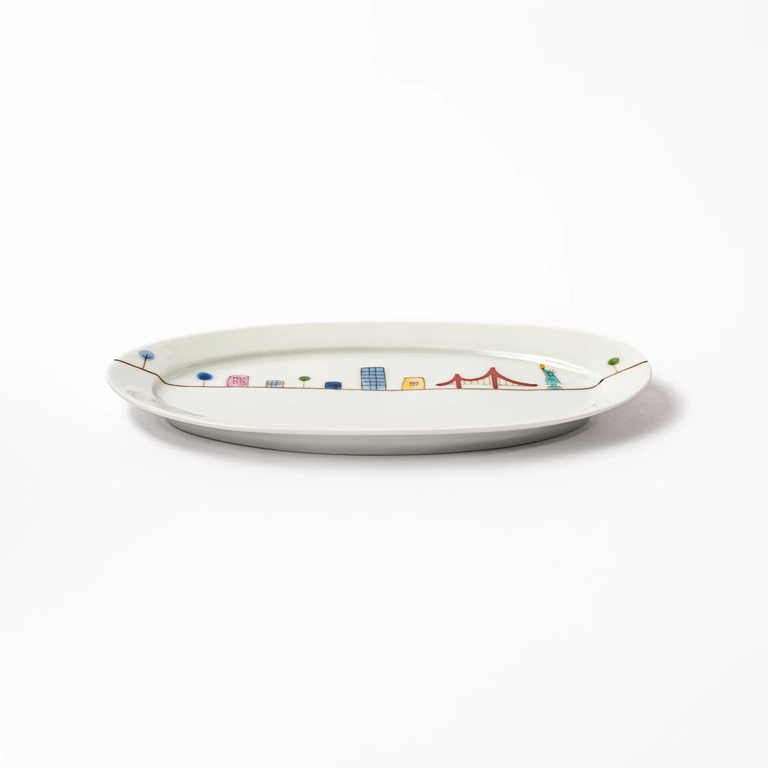Japanese porcelain oval plate with playful USA cityscape design featuring Statue of Liberty, bridge, and colorful buildings