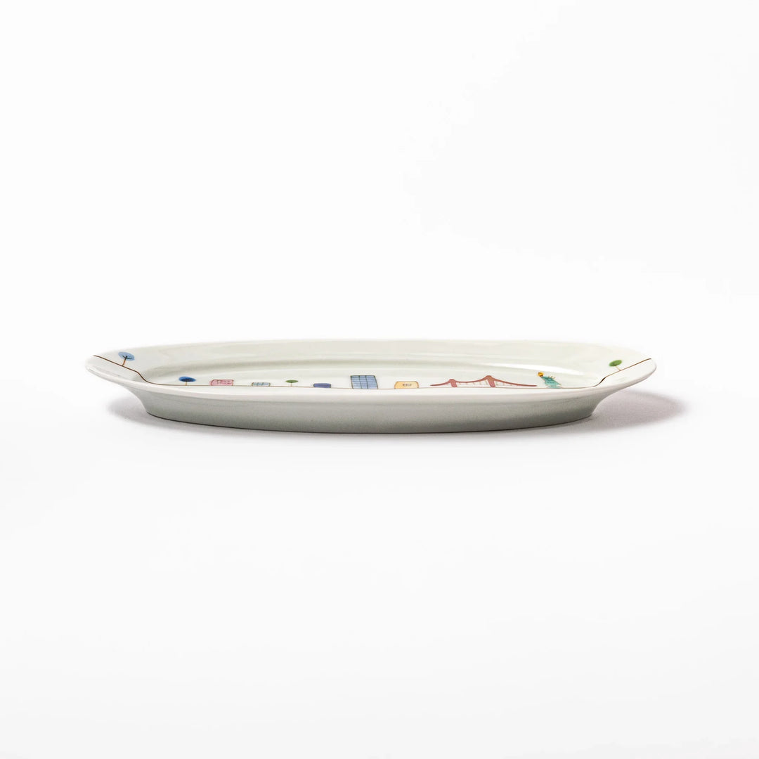 Japanese porcelain oval plate with playful USA cityscape design featuring Statue of Liberty, bridge, and colorful buildings