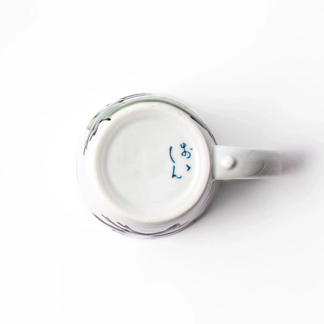 White ceramic kids mug featuring green T-Rex dinosaur graphic with yellow accents and blue cloud motifs, round handle