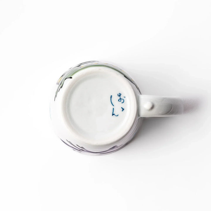 White ceramic kids mug featuring green T-Rex dinosaur graphic with yellow accents and blue cloud motifs, round handle