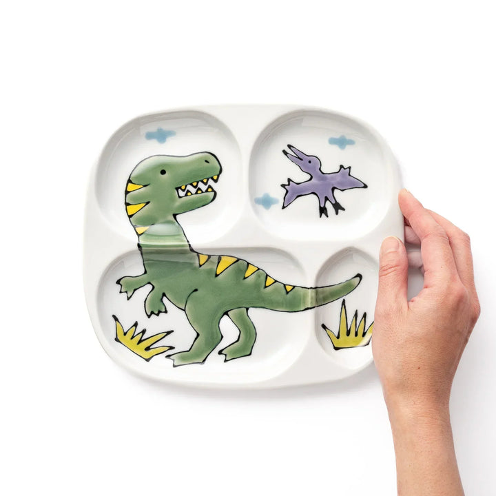 White ceramic kids divided plate with green T-Rex, purple pterodactyl, yellow grass and blue cloud accents