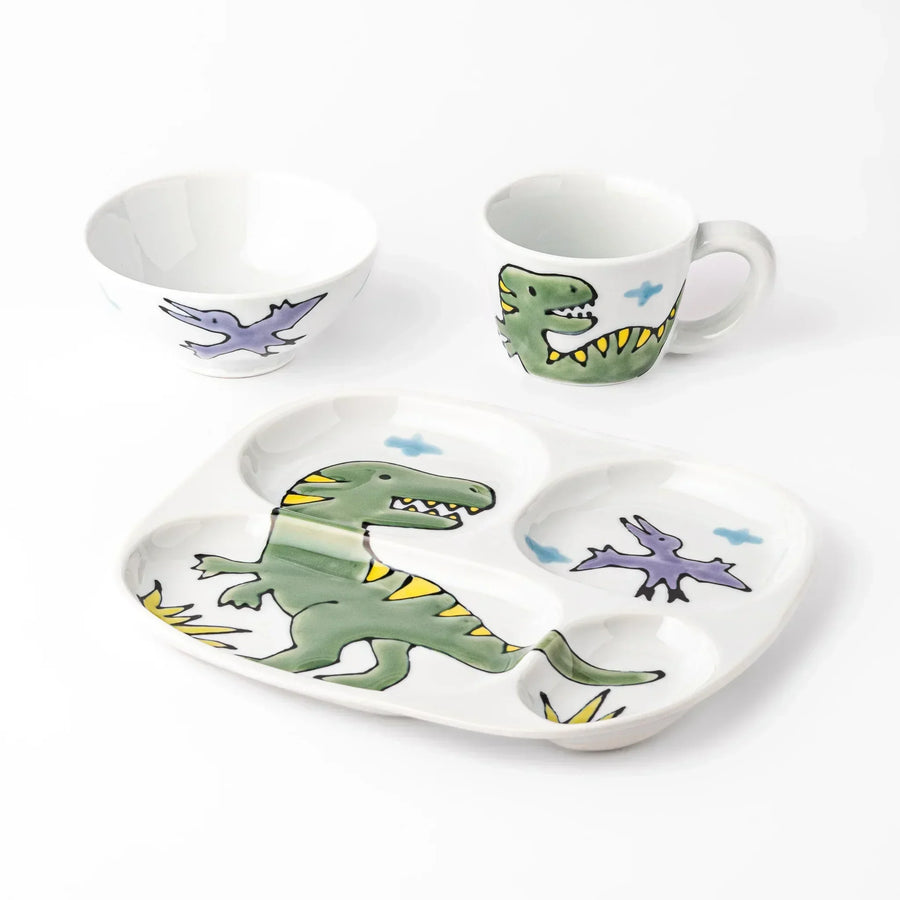 White ceramic kids mug, divided plate and rice bowl set featuring green T-Rex dinosaur graphics and blue cloud accents