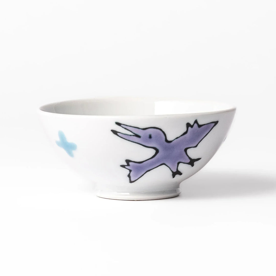 White ceramic kids rice bowl featuring green T-Rex dinosaur graphic with yellow accents and blue cloud motifs