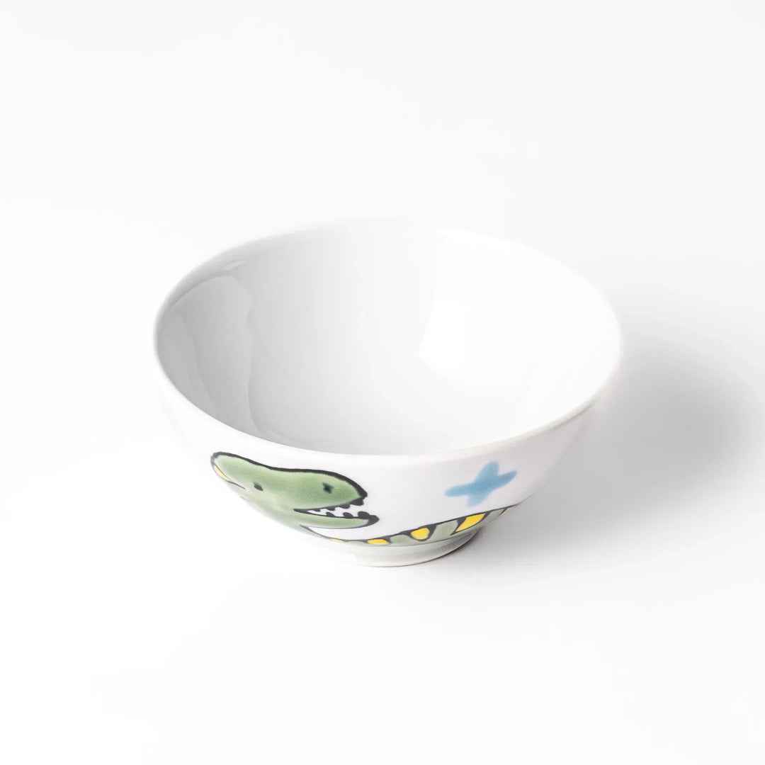 White ceramic kids rice bowl featuring green T-Rex dinosaur graphic with yellow accents and blue cloud motifs