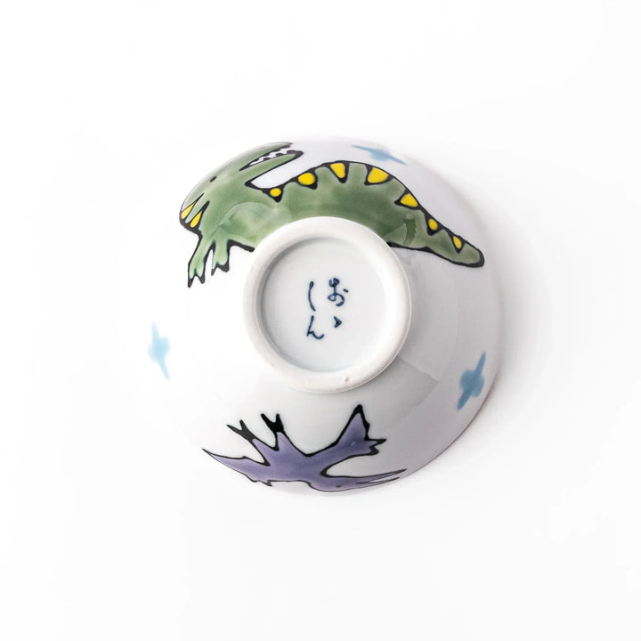 White ceramic kids rice bowl featuring green T-Rex dinosaur graphic with yellow accents and blue cloud motifs