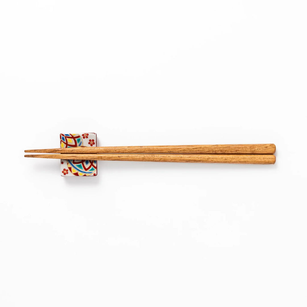 Rectangular Japanese ceramic chopstick rest with colorful temari ball and red floral patterns for dining.