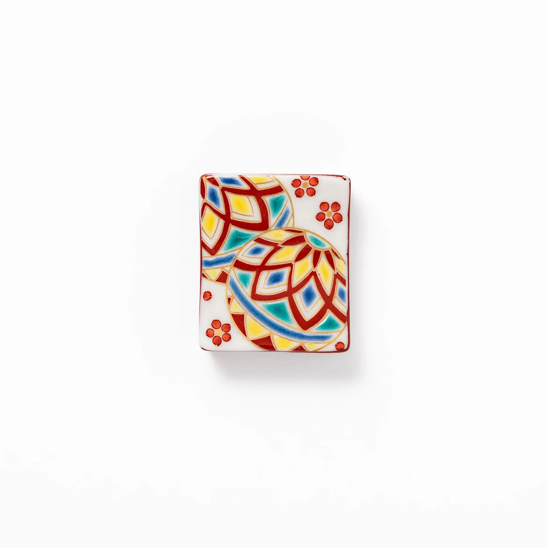 Rectangular Japanese ceramic chopstick rest with colorful temari ball and red floral patterns for dining.
