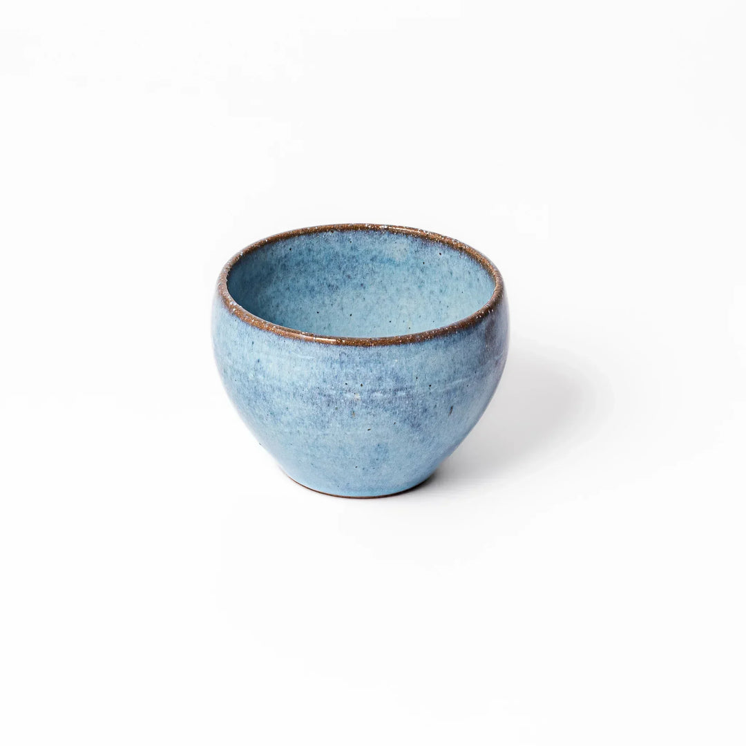 Terracotta blue ceramic tea cup with rustic brown rim, handcrafted in Japan for enjoying tea, coffee, or warm drinks.