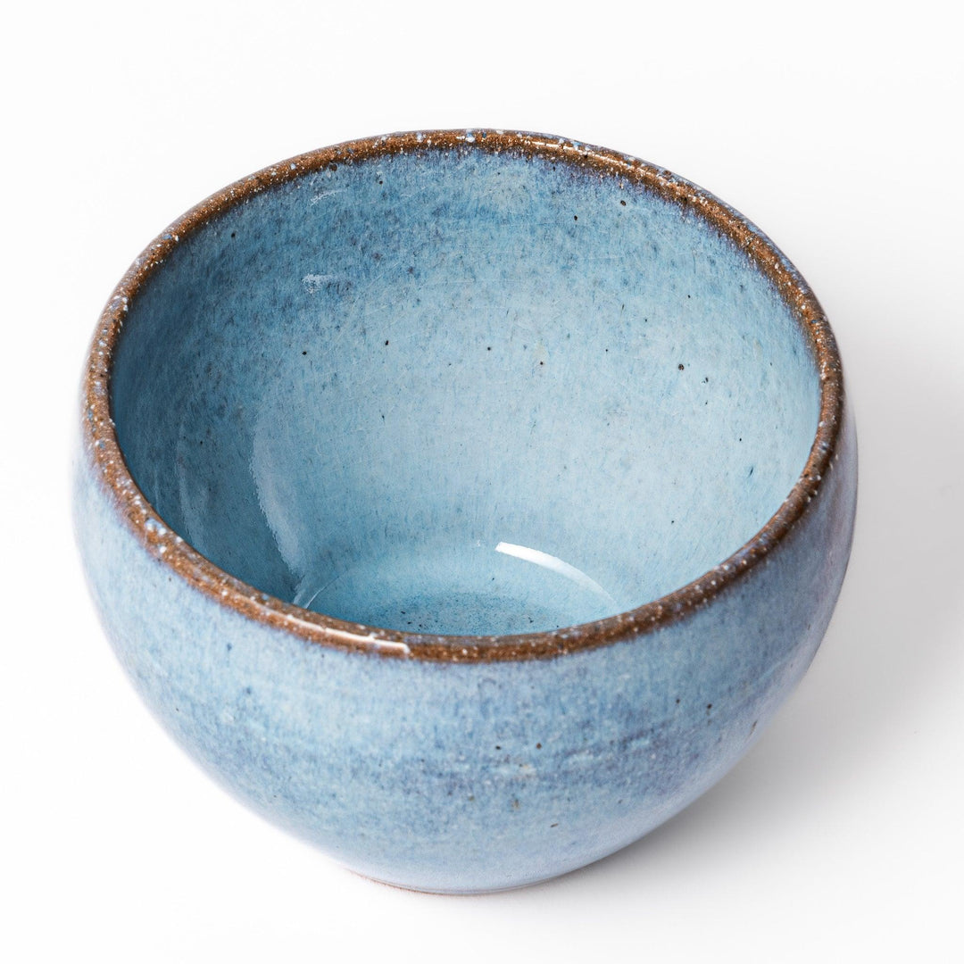 Terracotta blue ceramic tea cup with rustic brown rim, handcrafted in Japan for enjoying tea, coffee, or warm drinks.