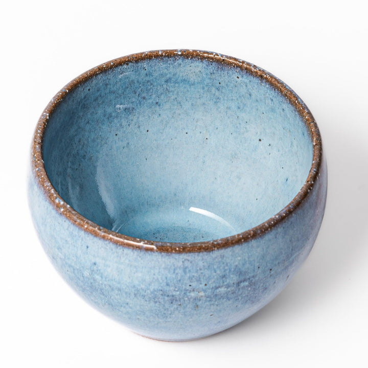 Terracotta blue ceramic tea cup with rustic brown rim, handcrafted in Japan for enjoying tea, coffee, or warm drinks.
